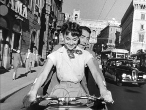 1280px-Audrey_Hepburn_and_Gregory_Peck_on_Vespa_in_Roman_Holiday_trailer
